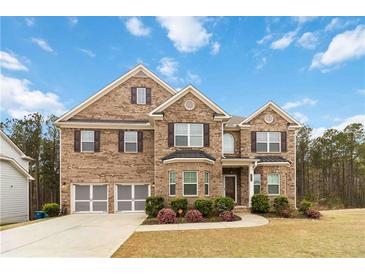 Charming two-story brick home featuring a two-car garage, manicured lawn, and beautifully landscaped front yard at 3478 Spring Place Ct, Loganville, GA 30052