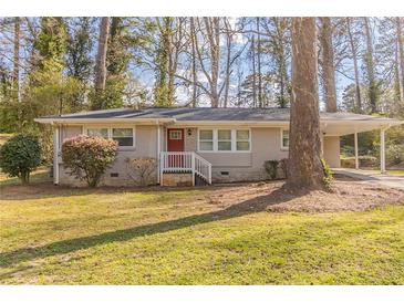 Charming single-story home with a carport and well-manicured lawn and an inviting red front door at 3475 Glensford Dr, Decatur, GA 30032