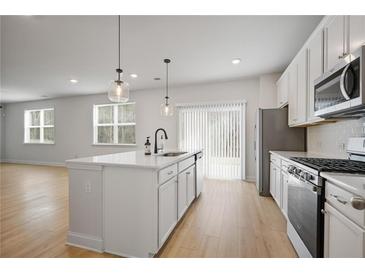 Bright kitchen featuring a kitchen island with sink, stainless appliances, and sliding glass door at 5 Dew Drop Pt, Dallas, GA 30157