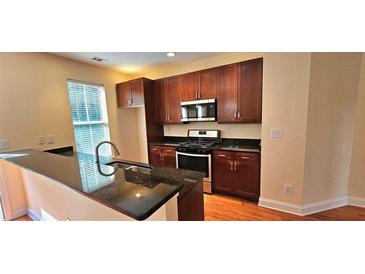 Well-lit kitchen features dark wood cabinets, stainless steel appliances and granite countertops at 5905 Brookside Oak Cir, Norcross, GA 30093