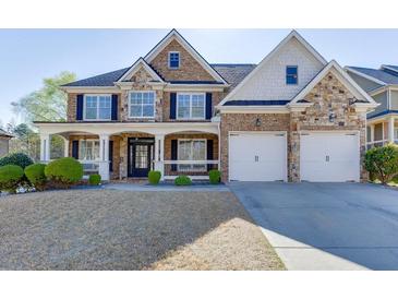 Charming two-story home features a stone and brick facade, a welcoming porch, and a manicured front yard at 2546 Summer Song Way, Buford, GA 30519