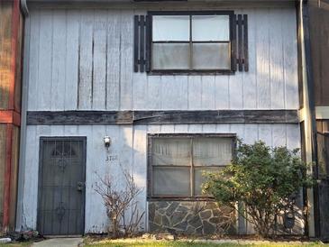 Modest exterior of a two-story home with a gray facade, windows, and front door with iron grate at 3788 Travis Trce, Decatur, GA 30032
