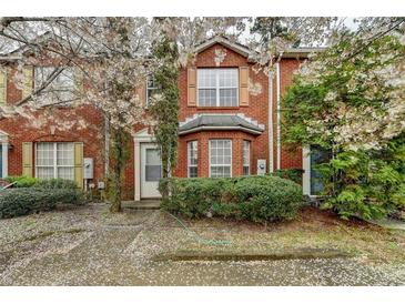 Charming red brick townhome featuring a well-manicured lawn and flowering trees at 2892 Norfair Ne Loop, Lithonia, GA 30038