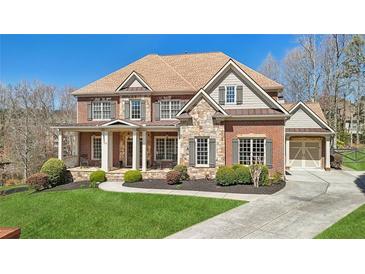 Beautiful two-story brick home with manicured lawn, stone accents, and charming front porch at 3149 Hidden Falls Ne Dr, Buford, GA 30519