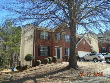 Charming two-story brick home with black shutters, a lawn with pruned bushes, and a driveway with parked cars at , College Park, GA 30349