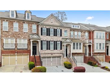 Beautiful townhome exterior featuring brick, stone accents, and symmetrical windows with black shutters at 2517 Ashwicke Se Dr, Atlanta, GA 30339