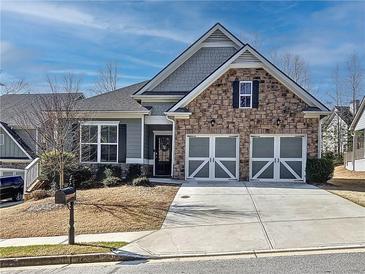Charming home featuring a stone facade, two-car garage, and well-maintained landscaping at 142 Richmond Way, Villa Rica, GA 30180