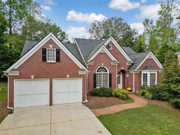 Charming red brick home featuring a two-car garage, manicured lawn, and a brick walkway leading to the front door at 2121 Whitekirk Nw St, Kennesaw, GA 30152