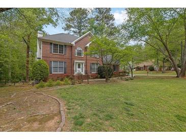 Two-story brick home with a well-manicured front lawn and mature trees, offering great curb appeal at 7037 Waters Edge Dr, Stone Mountain, GA 30087