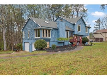 Two story home with a mix of wood and stone exterior, front yard with blue sky and mature trees at 2735 Peachtree Walk, Duluth, GA 30096