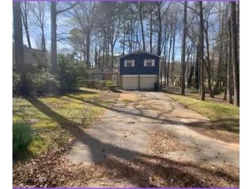 Two-story home with a blue facade, set amongst trees with a two-car garage and lengthy driveway at 2943 E Howell Dr, Lawrenceville, GA 30044