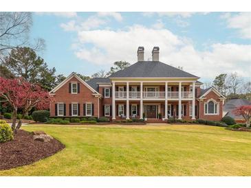 Stately brick home with a large front lawn, covered balcony, and double front doors exuding curb appeal at 1100 Muirfield Ct, Alpharetta, GA 30005
