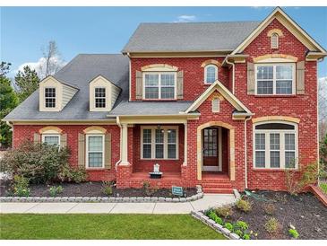 Beautiful two-story brick home with landscaped front yard and charming architectural details at 2220 Stirling Bridge Rd, Cumming, GA 30041