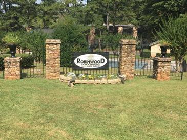Inviting Robinwood Condominiums entrance featuring brick pillars, manicured lawn, and colorful flower beds, offering a warm welcome at 2340 Beaver Ruin Rd # 89, Norcross, GA 30071