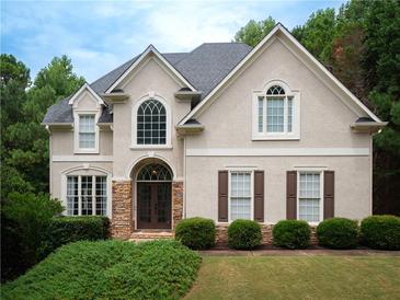 Charming two-story home featuring a well-maintained lawn, symmetrical shrubbery, and stone accents on the front entrance at 507 Autumn Walk, Canton, GA 30114