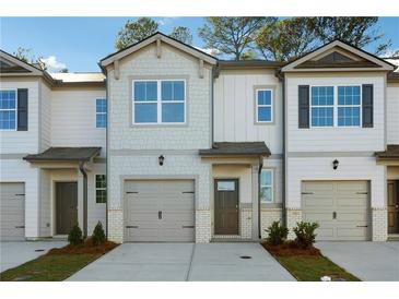 Charming townhome featuring a gray exterior, complemented by a matching one-car garage and well-maintained landscaping at 2272 Jamin Bnd # 13, Lithonia, GA 30058