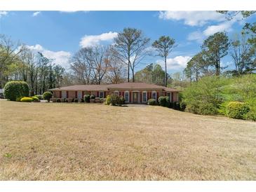 Charming ranch-style home with brick facade, surrounded by manicured shrubs and a large front yard at 4892 Duncan Dr, Powder Springs, GA 30127