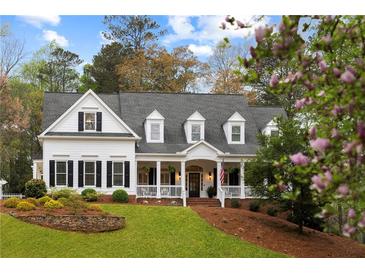 Charming two-story home with a welcoming front porch and meticulously landscaped front yard and shuttered windows at 12680 Old Surrey Pl, Roswell, GA 30075