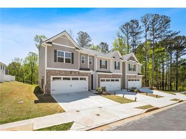 Three newly built townhomes featuring a brick facade, attached garages, and a well-manicured lawn at 1180 Cades Walk, Lawrenceville, GA 30045