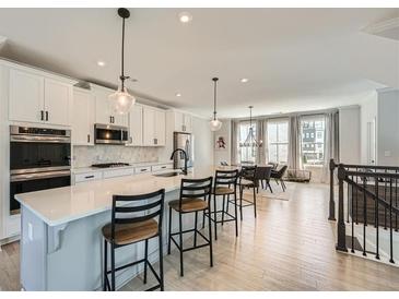 Bright, open-concept kitchen featuring a large island, stainless steel appliances, and seamless flow into the dining area at 6187 Kelly Carlin Way, Norcross, GA 30071
