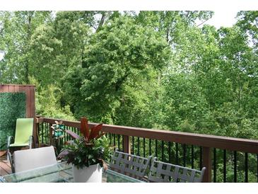 A relaxing outdoor space with a glass table, chairs, and lush greenery with trees visible from the wooden deck at 2022 Raven Way, Atlanta, GA 30341