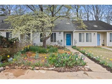 Charming townhouse with vibrant flower garden and a bright blue front door at 9023 Stoneleigh Trce, Douglasville, GA 30134