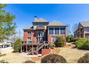 A two-story brick home featuring a large deck and patio surrounded by a lush landscaped yard at 1037 Windermere Xing, Cumming, GA 30041