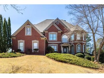 Charming two-story red brick home with a manicured lawn and mature landscaping on a sunny day at 1037 Windermere Xing, Cumming, GA 30041