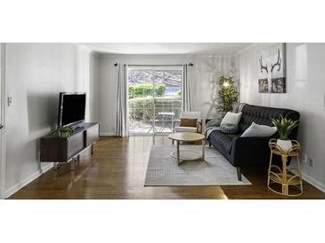 Bright living room with hardwood floors, stylish furniture, and a sliding glass door to a patio at 2955 Seven Pines Se Ln # 203, Atlanta, GA 30339