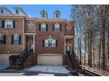 Charming brick townhome with two-car garage and inviting front entrance with black iron railings and American flags at 600 Jardin Ct # 48, Alpharetta, GA 30022