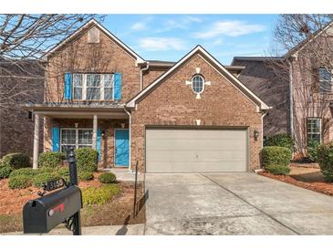 Charming brick home with a two-car garage and blue accents, enhanced by lush landscaping at 3455 Flycatcher Way, Duluth, GA 30097