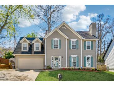 Two-story home featuring light gray siding, dormer windows, attached garage, manicured lawn, and shutters at 880 Hillary Ln, Lawrenceville, GA 30043