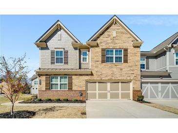 Charming two-story home featuring a brick and stone facade, complemented by shutters and a two-car garage at 2910 Bishopstone Way, Cumming, GA 30040