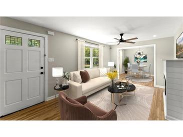 Bright living room featuring hardwood floors, a ceiling fan, a fireplace, and ample natural light at 3524 Brookfield Ln, Decatur, GA 30032