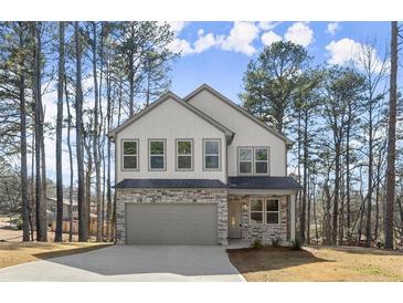Charming two-story home featuring stone accents and a gray garage door with a large concrete driveway at 3170 Old Hwy 92 Dr, Acworth, GA 30102