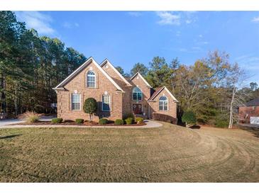 Two-story brick home featuring arched windows, a manicured lawn, and mature trees at 1415 Swiftwater Cir, Mcdonough, GA 30252