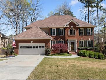 Charming brick home featuring a two-car garage, manicured lawn, mature trees, and attractive landscaping at 960 Whitehawk Trl, Lawrenceville, GA 30043