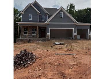 New construction home with gray siding, brick accents, and a three-car garage at 174 Pinewood Dr, Covington, GA 30014