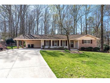 Charming single-story home featuring a brick facade, a carport, and a lush, well-maintained lawn at 5836 Trailwoods Ct, Stone Mountain, GA 30087