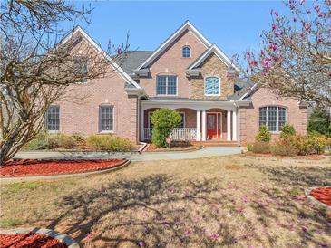 Charming two-story brick home with a manicured lawn, flowering trees, and welcoming front porch at 612 Kristen Ct, Mcdonough, GA 30252