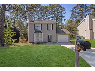 Charming two-story home featuring a landscaped yard, attached garage and large front windows at 2143 Victoria Pl, Lithonia, GA 30058