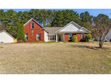Charming brick and white home featuring a well-manicured lawn and beautiful landscaping at 1703 Mission Park Dr, Loganville, GA 30052