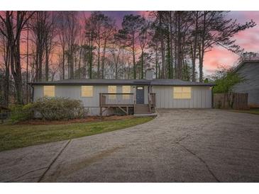 Charming single-story home with a gray exterior, inviting front porch, and a long driveway surrounded by mature trees at 4953 Apple Valley Rd, Douglasville, GA 30135