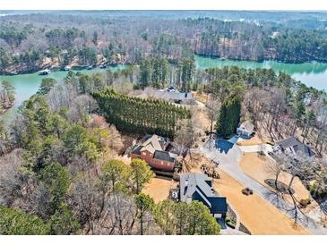 Expansive aerial view of a lakefront home with mature trees and lush landscaping around the property at 3795 Duckcove Way, Cumming, GA 30041