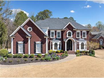 A brick two-story home with a well-manicured lawn, elegant landscaping, and a symmetrical design at 3795 Duckcove Way, Cumming, GA 30041