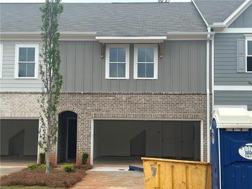 Two-story townhome featuring a gray-brick exterior with open garage, perfect for modern living at 113 Priestwood Ln, Acworth, GA 30102