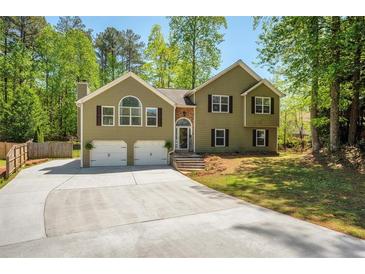 Charming home featuring a two-car garage, beautiful landscaping, and a well-maintained front yard at 404 Queensbury Pl, Acworth, GA 30102