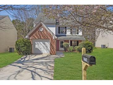 Charming two-story home with manicured lawn, brick accents and a lovely, blooming tree at 7176 Ravenwood Ln, Lithonia, GA 30038