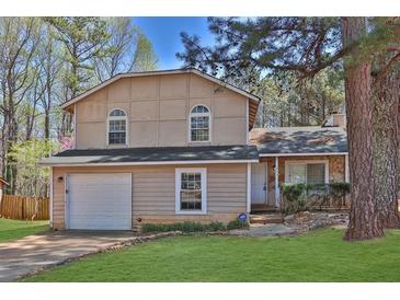Charming two-story home with a well-manicured lawn and attached garage, complemented by mature trees at 1045 Forest Path, Stone Mountain, GA 30088