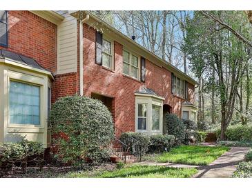 Charming red brick townhome featuring a bay window and well-manicured front yard at 1384 Sheffield Glen Ne Way, Atlanta, GA 30329